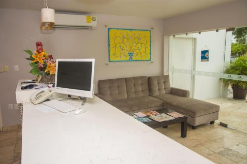 ein Wohnzimmer mit einem Sofa und einem Computer auf dem Schreibtisch in der Unterkunft Hotel Casa Blanca in Chetumal