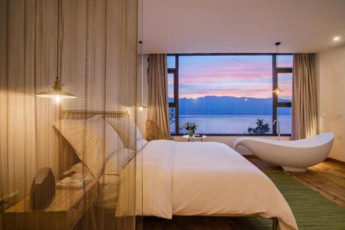 大理市にある大理远山青Stone Hill悬崖海景民宿 Dali Verdant Whisper-Stone Hill Seaview Innのベッドルーム(バスタブ、ベッド1台、大きな窓付)
