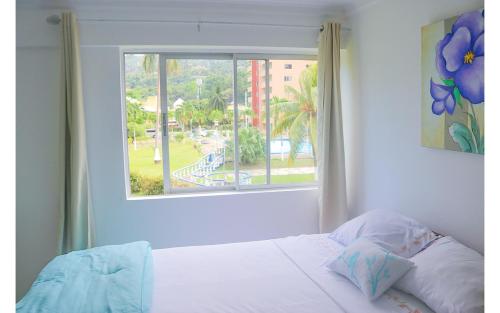 a bedroom with a bed and a window with a view at Beach Side Suite At Turtle Towers in Ocho Rios