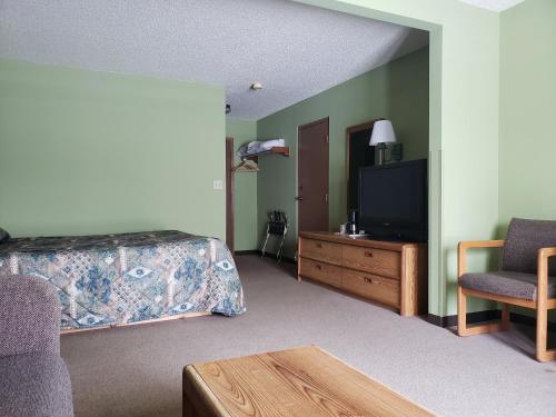 a bedroom with a bed and a tv and a chair at Harbor Lights Lodge in Kewaunee
