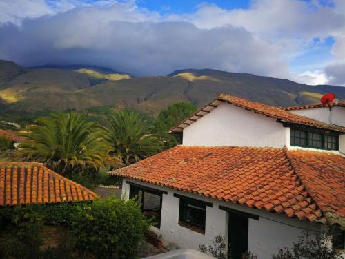 a house with an orange roof with mountains in the background at Hotel El Giro in Villa de Leyva