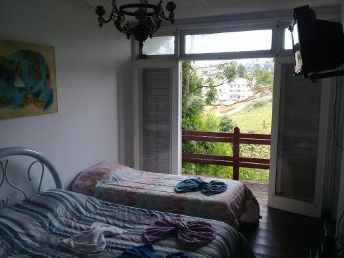 a bedroom with two beds and a window with a view at Casa Green Vista in Campos do Jordão
