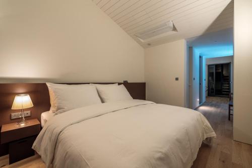 a bedroom with a large white bed and a lamp at Hotel 498 in Incheon