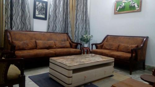 a living room with two leather couches and a coffee table at I.K Homestay in Kohīma