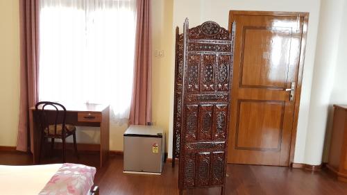 a room with a bed and a door and a desk at Woodland Hill Stay in Shillong