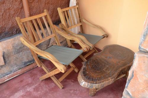 two wooden chairs and a turtle next to a wall at Hoima Cultural Lodge in Hoima