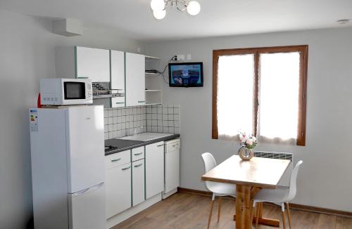 a kitchen with a white refrigerator and a table at alpes studio in Feissons-sur-Salins