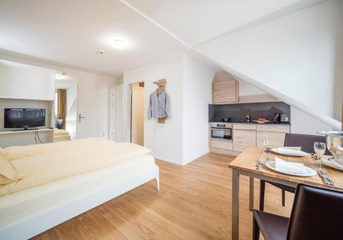 Aparthotel Bären في Seengen: غرفة نوم بسرير وطاولة ومطبخ