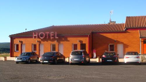 uma fila de carros estacionados em frente a um hotel em Auberge De Peyrebeille em Lanarce