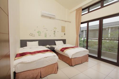 2 camas en una habitación con ventana en Sanyi Sakura Resort, en Sanyi