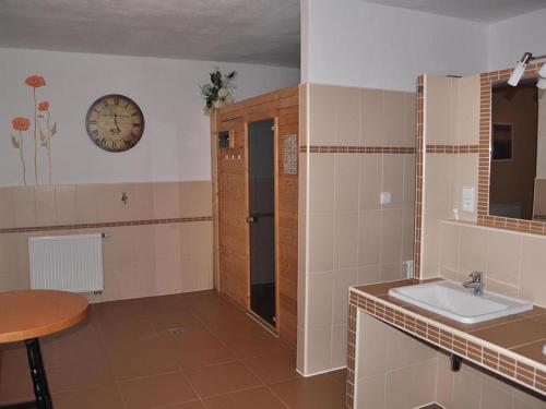 een badkamer met een wastafel en een klok aan de muur bij Villa Frymburk in Frymburk
