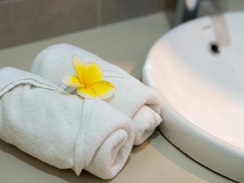 a towel with a flower on it next to a sink at Baleka Resort & Spa in Legian