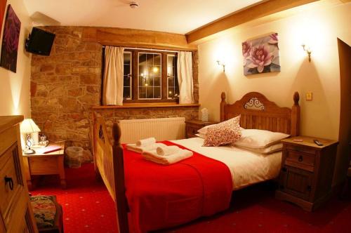 um quarto com uma cama com um cobertor vermelho em The George Inn & Millingbrook Lodge Ltd em Lydney