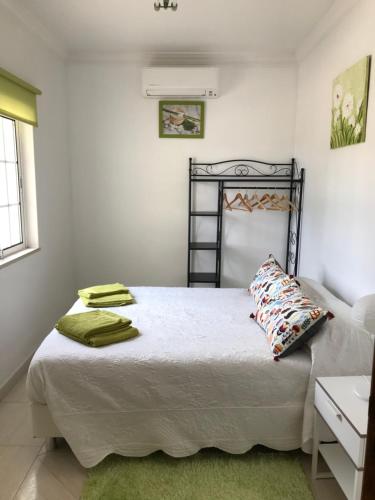een slaapkamer met een bed met witte lakens en groene kussens bij Villa Estrelamar in Boliqueime