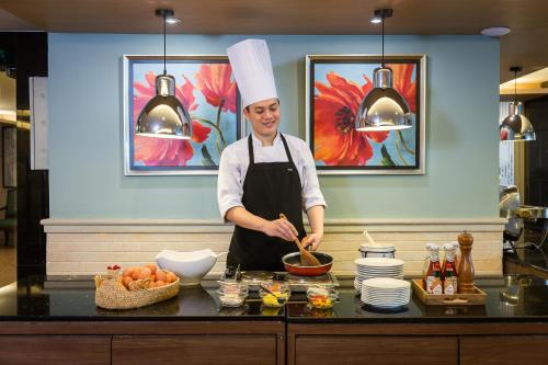 a chef standing in a kitchen preparing food at Evergreen Place Siam by UHG in Bangkok