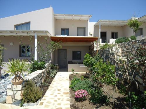a house with a stone retaining wall and a yard at Mythos Suites Diskos in Léntas