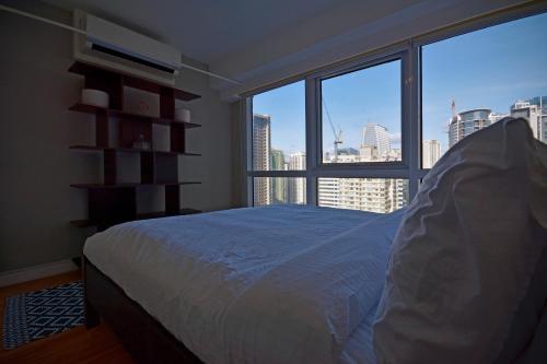 1 dormitorio con cama y ventana grande en Victoria SOHO Suites, en Manila