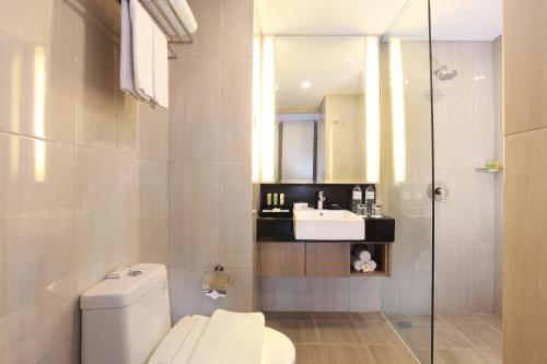 y baño con aseo y lavamanos. en Swiss-Belinn Tunjungan Surabaya, en Surabaya