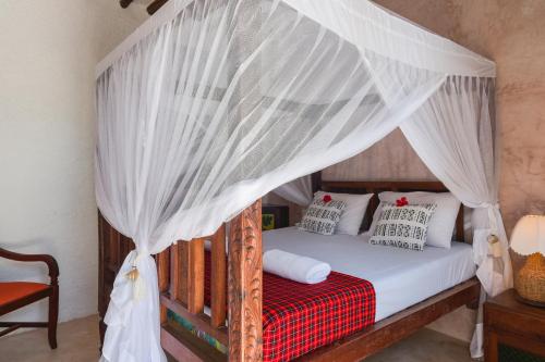 a bedroom with a canopy bed with white curtains at Villa Lala in Kiwengwa
