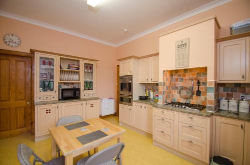 a kitchen with white cabinets and a wooden table at Knight's Rest Guest House in Airdrie