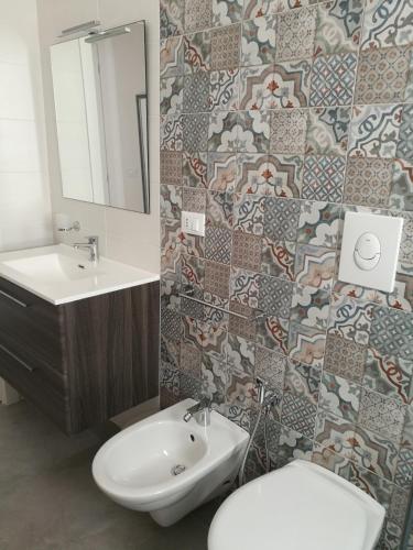 a bathroom with a sink and a toilet and a mirror at Manolo Case Vacanza in Monopoli