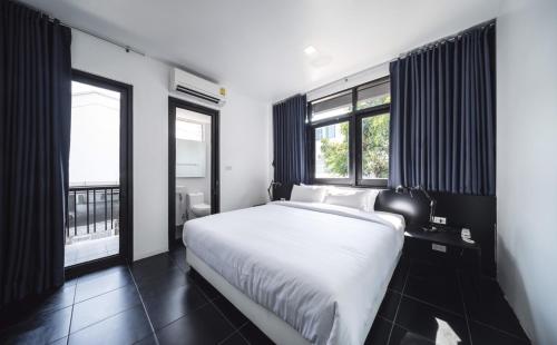 a bedroom with a white bed and two windows at The Common Hostel in Chiang Mai