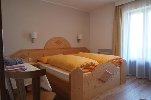 a bedroom with a wooden bed with yellow sheets at Unterbergerhof in Val di Vizze