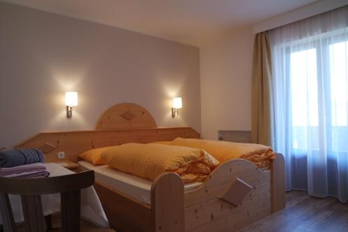 a bedroom with a wooden bed with a large window at Unterbergerhof in Val di Vizze