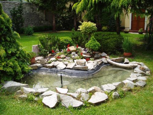 a garden with a pond with rocks in a yard at Hotel Wollner in Sopron