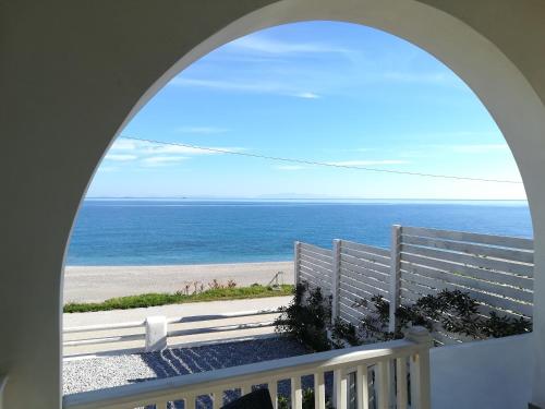 an archway view of the beach from a balcony at villa vagelis in Mourteri
