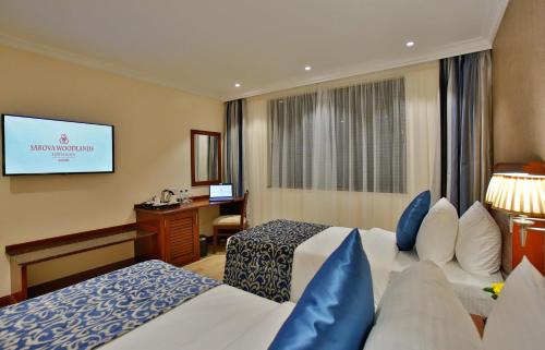 a hotel room with two beds and a television at Sarova Woodlands Hotel and Spa in Nakuru
