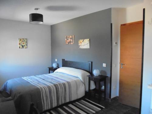 a bedroom with a bed and two tables and a door at Casa Rural la Iglesuela in El Barco de Ávila