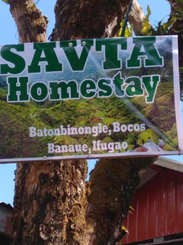 a sign on a tree in front of a building at Savta Homestay in Banaue