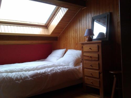 a bedroom with a bed with a window and a dresser at Appartements les Bressanes in Selonnet