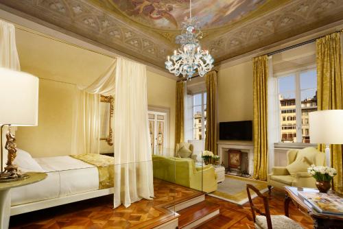 una camera con letto e un soggiorno con lampadario a braccio di Grand Hotel Minerva a Firenze