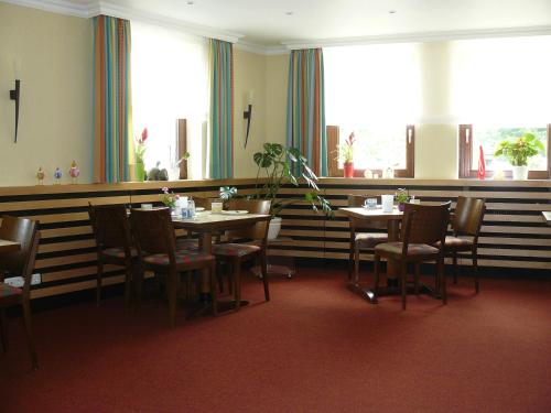 a dining room with tables and chairs and windows at Hotel Meyer in Hildesheim