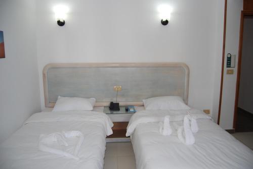two beds with white sheets and shoes on them at Acacia Dahab Hotel in Dahab