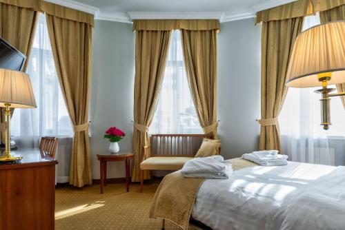 a hotel room with a bed and a chair and windows at My City Hotel in Tallinn