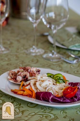 a plate of food on a table with wine glasses at Albergo Diffuso Mannois in Orosei