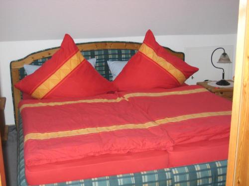 a bed with red and yellow pillows on it at Haus Pistorius in Büsum