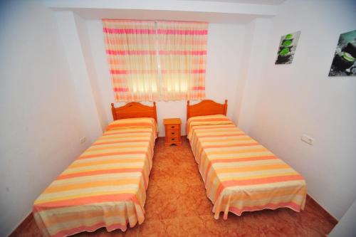 2 Betten in einem kleinen Zimmer mit Fenster in der Unterkunft ROQUER MARTÍ vista mar Orangecosta in Alcossebre
