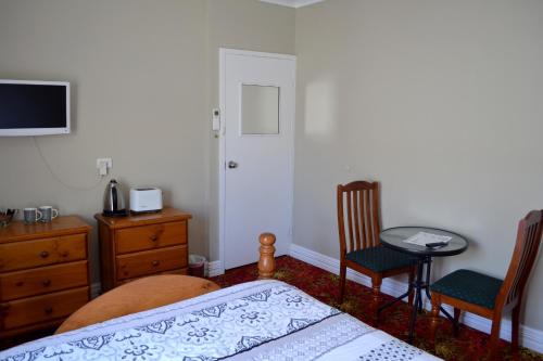 a bedroom with a bed and two chairs and a table at Ithaca 1896 Manor in Busselton