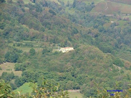 a house on top of a hill with trees at Hotel Rural Casa Migio in Urbiés