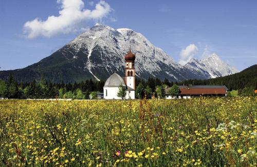a church in a field of flowers with a mountain at Haus Elisengrund am Geigenbuehel - chalet privé in Seefeld in Tirol