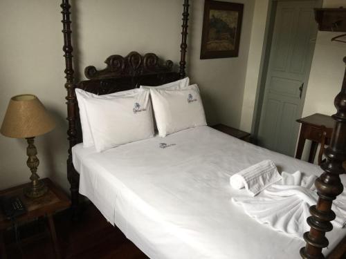 a bedroom with a large bed with white sheets and pillows at Pousada Solar da Inconfidência - fácil acesso a Praça Tiradentes in Ouro Preto