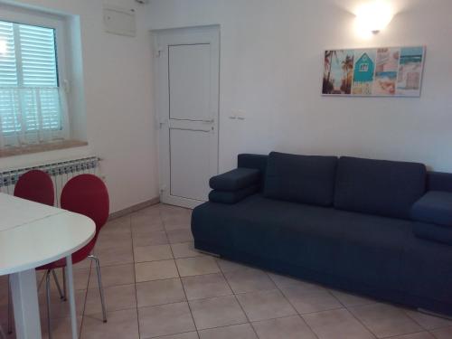 een woonkamer met een blauwe bank en een tafel bij Apartments Fuchs in Umag