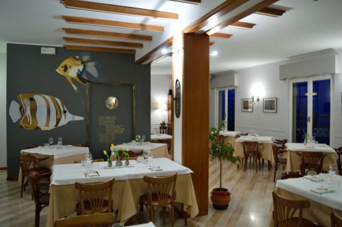 uma sala de jantar com mesas e cadeiras brancas em Hotel Bianchi Nicola em Porto Recanati