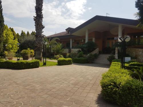 a house with a palm tree and a brick driveway at Agriturismo Terre Delle Monache in Pontecagnano