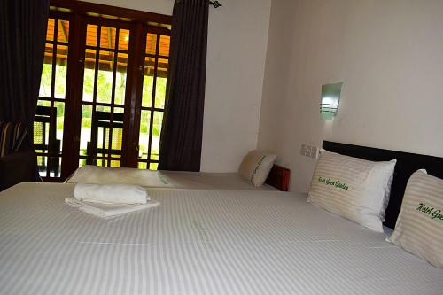 a bedroom with two beds and a window at Hotel Green Garden in Trincomalee