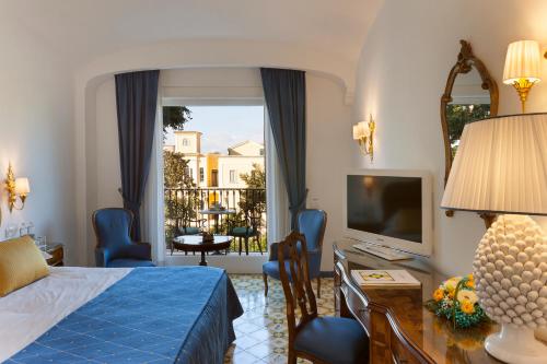 a bedroom with a bed and a desk and a television at Grand Hotel La Favorita in Sorrento